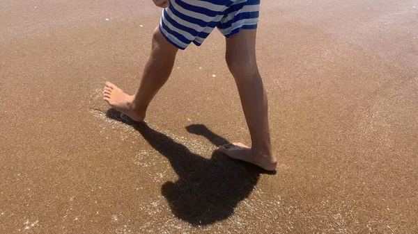 Child feet walking at the beach shore