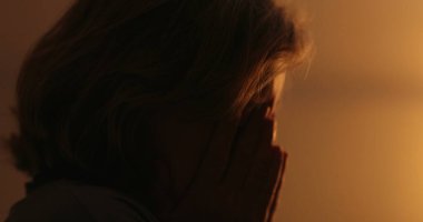 Anxious older woman suffering at night, close-up face. Troubled person rubbing face with hand
