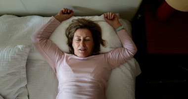 Happy person lying down in bed resting and relaxing