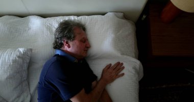 Older man resting in bed during afternoon nap