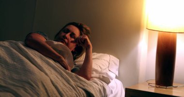 Person turning nightstand light on. Senior woman waking up in the middle of the night suffering from insomnia