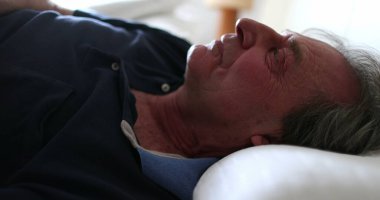 Older man waking up from afternoon nap. Person gets out of bed