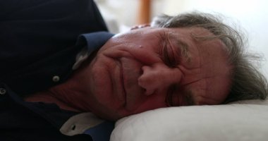 Old man lays down in bed to nap. Senior guy resting napping
