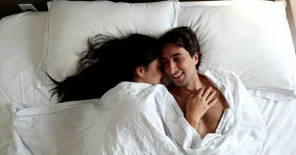 Couple lying in bed in the morning under blanket
