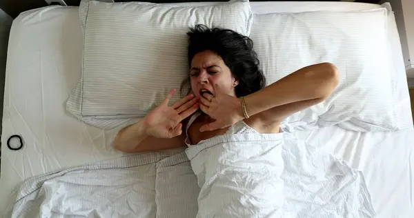 Young woman stretching in the morning waking up and getting out of bed