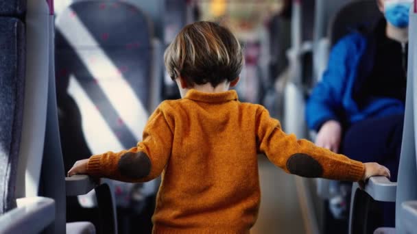 Ung Pojke Solig Gul Pullover Navigerar Tågkorridoren Händerna Griper Tag — Stockvideo