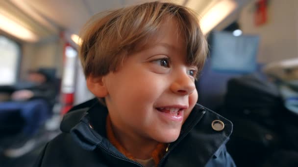 坐在火车上的是快乐的小男孩的近视脸 快乐的孩子乘坐高速火车旅行 特写笑脸 — 图库视频影像