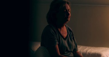 Senior woman getting up from bed at night. Tired person waking up at dawn