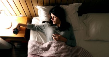 Woman turning OFF nightstand lamp light. Person turns OFF phone