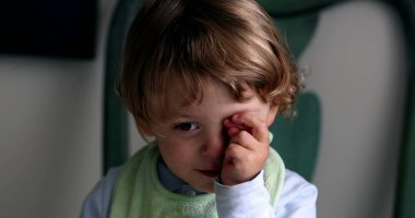 Baby rubbing eyes with hand. Cute toddler boy
