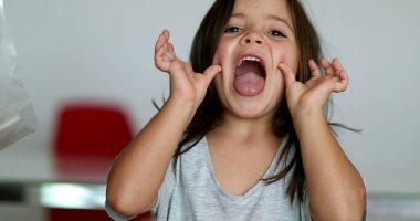 Little girl grimacing to camera sticking tongue out. Child teasing