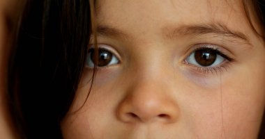 Thoughtful little girl macro close-up face. Pensive child looking at camera