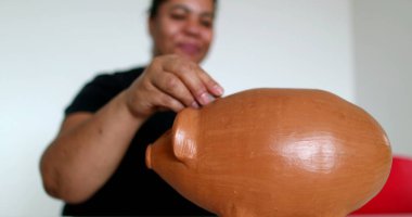 African woman inserting coins inside piggy bank