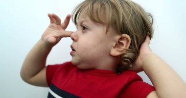 Tired toddler boy rubbing eye with hand. Sleepy baby child