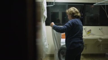 Çamaşır askısında kurutmak için çamaşırlarını koyan yaşlı bir kadın. Ev işlerini yapan yaşlı bir adamın gerçek hayat sahnesi.