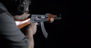 Kalaşnikof silahını 800 fp yavaş çekimde yüksek hızda ateşliyor. AK-47 tüfeğini hedef alan ve ateşleyen kişi. Silah hızı rampası
