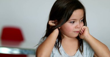 Tired little girl rubbing eyes with hands