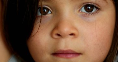 Thoughtful little girl macro close-up face. Pensive child looking at camera