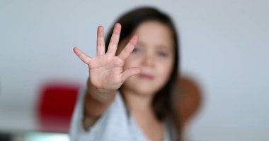 Little girl saying NO with hand. Child gesturing to STOP