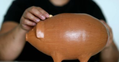 African woman inserting coins inside piggy bank