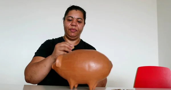 Person saving money putting pennies inside piggy bank