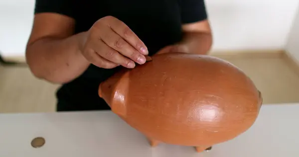 Hands putting coins inside piggy bank
