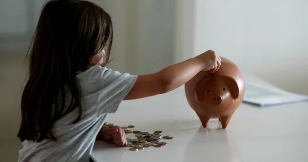 Child adding coins inside piggy bank