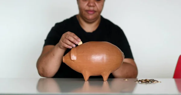 African woman inserting coins inside piggy bank