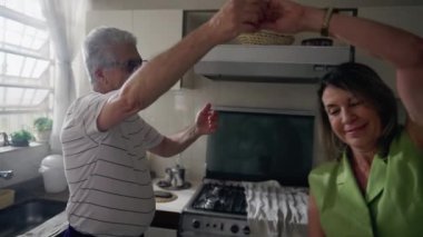 Mutlu romantik yaşlı çift mutfakta dans ediyor, emekli son sınıf öğrencisi, neşe içinde sarılıp dans ederek altın yılların tadını çıkarıyor.