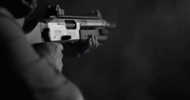 Güçlü bir av tüfeği ateşleyen ve mermileri siyah-beyaz dolduran kişinin tek renkli görüntüsü.