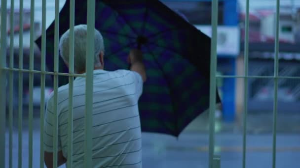 Älterer Mann Tritt Regen Aus Öffnet Regenschirm Und Geht Auf — Stockvideo