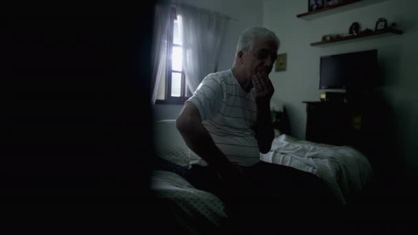 Przemyślany Starszy Mężczyzna Rozważa Decyzję Siedząc Przy Łóżku Ponurym Pokoju — Wideo stockowe