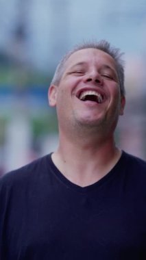 Orta yaşlı adam dikey videoda kameraya gülümseyip gülüyor.