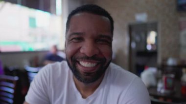 Geleneksel kafeterya restoranında kameraya gülümseyen mutlu bir siyah Brezilyalı adam. Neşeli bir insan portresini yakından çek.