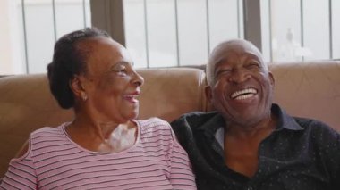 Kanepede oturup sohbet eden mutlu siyahi bir çift. Afrika kökenli Amerikalı karı-koca yaşlılık ilişkisi