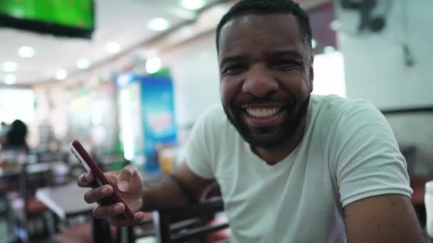 African American Guy Turning Head Phone Device Sitting Restaurant Joyful — Stock Video