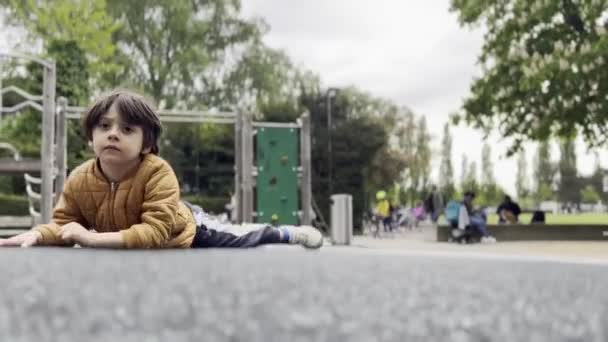 Exploração Lúdica Boy Spins Playground Platform Deitado Bruços Olhando Para — Vídeo de Stock