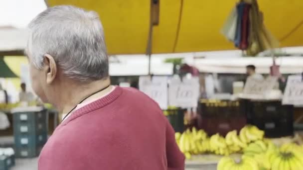 灰发巴西人漫步街头市场 在蔬菜和水果中 裸露香蕉 — 图库视频影像