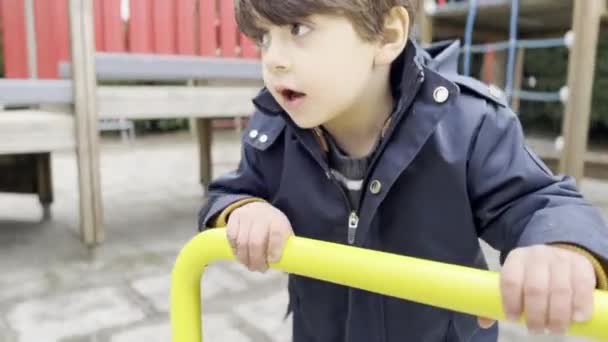 秋の遊び場のカルーセルで吸収された少年 ルーチンで昼間の楽しみ — ストック動画