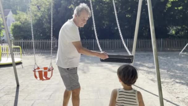 Zabawa Placu Zabaw Dziadek Prowadzi Wnuka Huśtawce Słoneczny Dzień Dla — Wideo stockowe