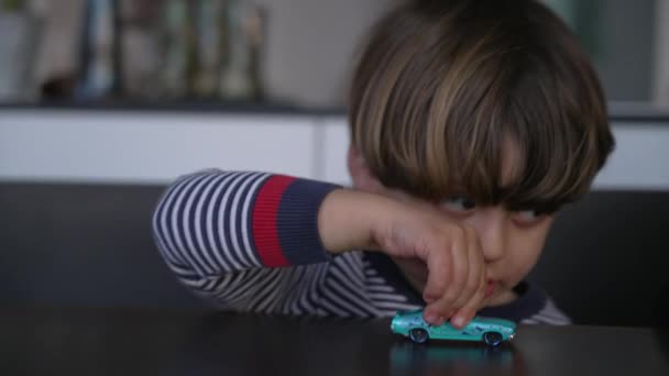 特写小孩玩玩具车 一个高加索小男孩把车体放在桌子上 — 图库视频影像