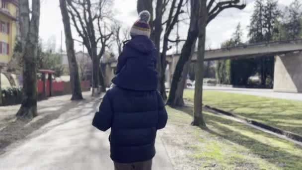 Hoş Gezinti Baba Oğlu Omuzlarda Taşır Ağaçlar Arasında Kaldırım Yolu — Stok video