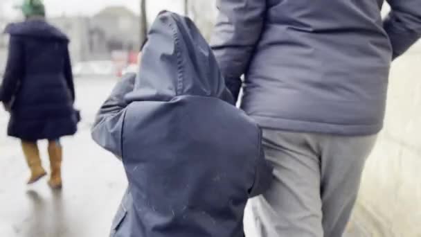 雨のストロール ジェントルドリズルの街歩道に沿ってコージーな服の母とボーイ — ストック動画