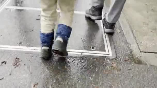 雨中的城市小径 脚踏在潮湿的人行道上 母亲和儿子穿着舒适的衣服 — 图库视频影像