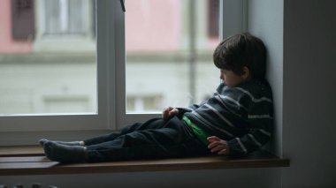 Tembel çocuk, dairesinin penceresinden kayıyor, dürüst, sıkıcı çocuk evde, yapacak bir şey yok, çocuk evde kapalı.