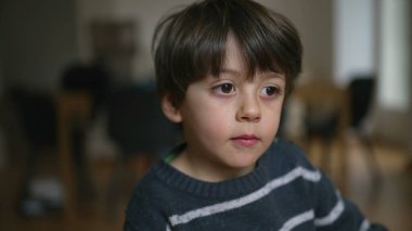 Kapalı mekanda nötr bir ifadeyle kameraya bakan 4 yaşındaki bir çocuğun portresi