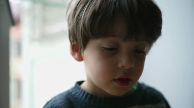 Dalgın, küçük çocuk, yakın çekim yüzü. Derin düşüncelere dalmış bir çocuk.