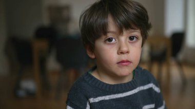 Kapalı mekanda nötr bir ifadeyle kameraya bakan 4 yaşındaki bir çocuğun portresi