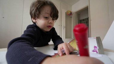 Kalem tutan çocuk yoğunlaştırılmış duygularla boyama kitabına çizim yapıyor. Okul ödevi yapan nişanlı bir çocuk.