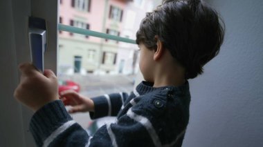 İkinci katın kapı kolunu tutan küçük bir çocuk. Çocuk güvenliği kavramı.